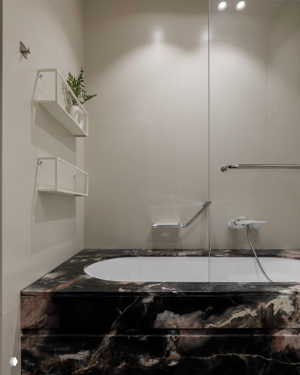 Ванная комната с встроенной ванной в подиуме из тёмного мрамора, минималистичные полки и стеклянная перегородка душа.