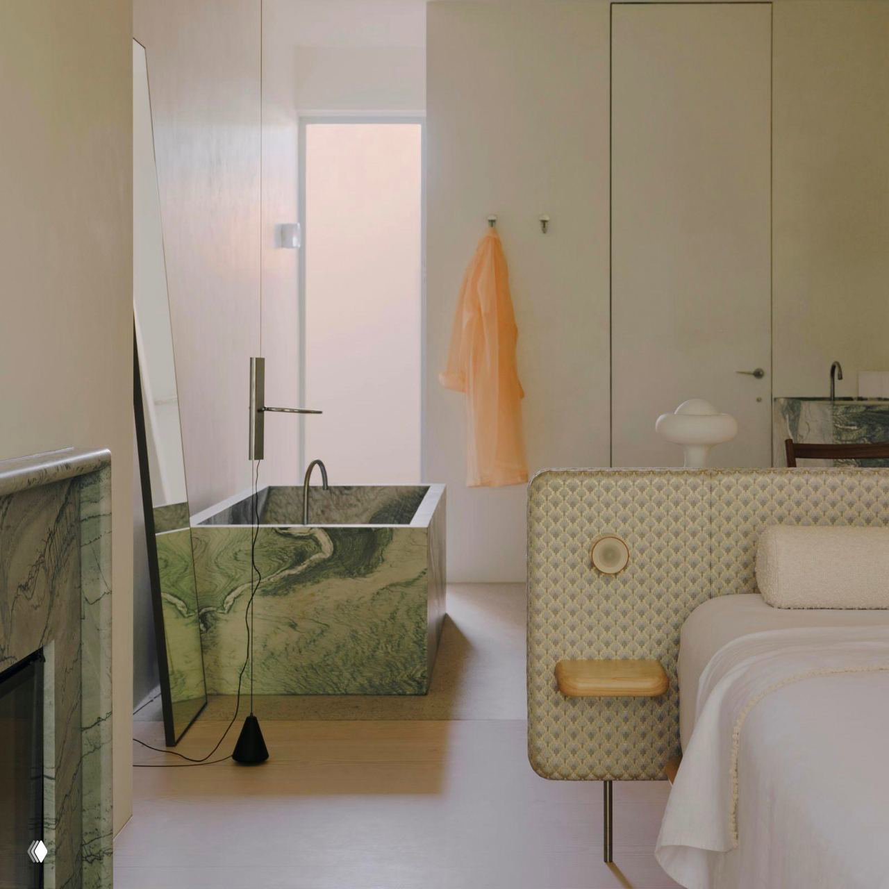 Квадратная мраморная ванна рядом с кроватью, минималистичное оформление и мягкие пастельные тона создают спокойный расслабляющий вид.