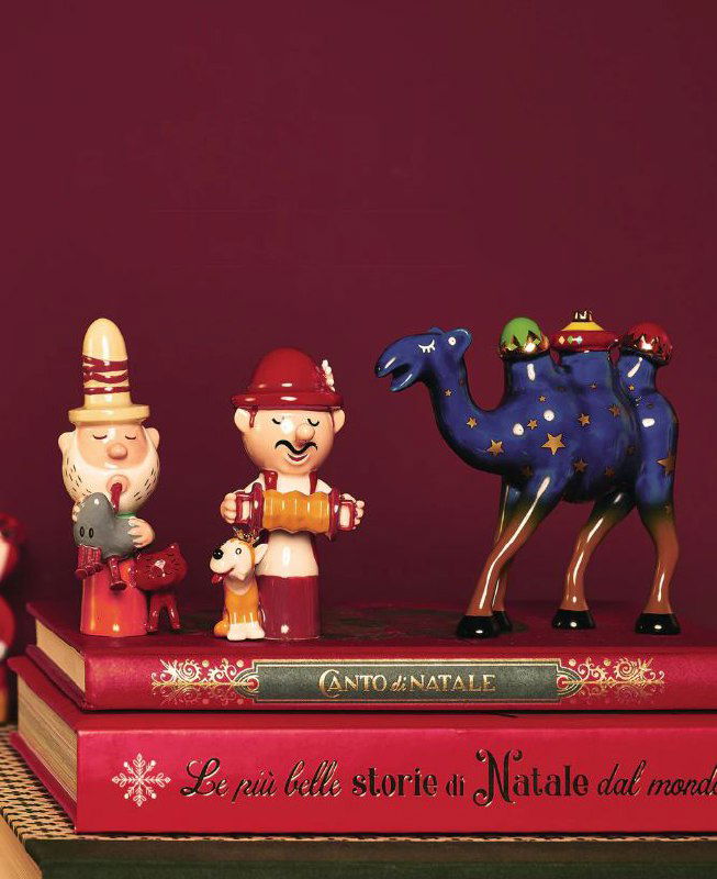 Набор керамических фигурок и декоративных персонажей Рождества на стопке подарочных изданий — игрушки и фигурки из рождественской линейки Alessi.
