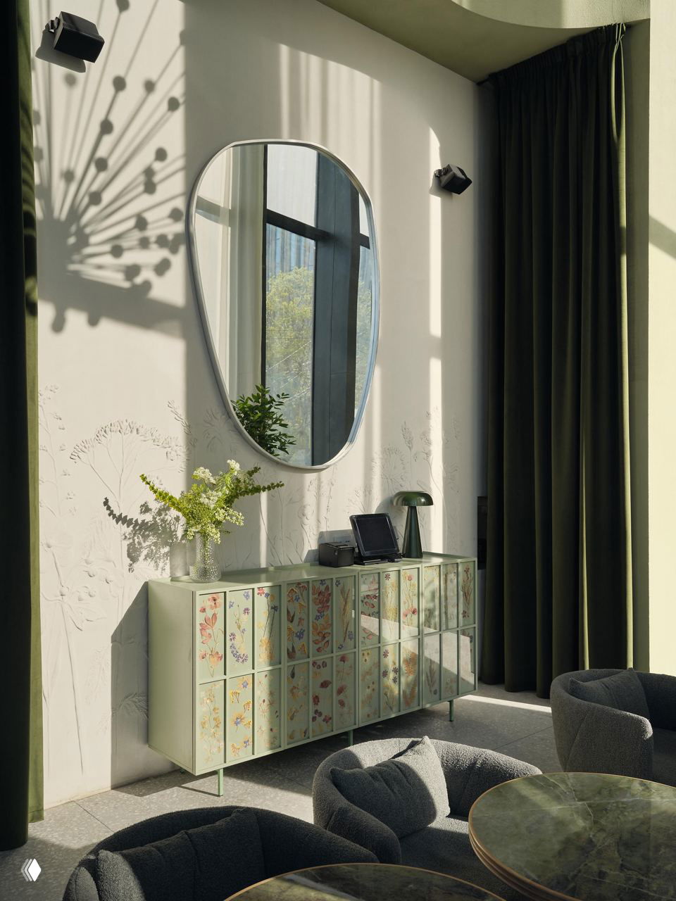 Деталь интерьера: декоративное зеркало на фоне тиснёной стеновой отделки, комод с флористическим декором и композиция из полевых цветов в вазе