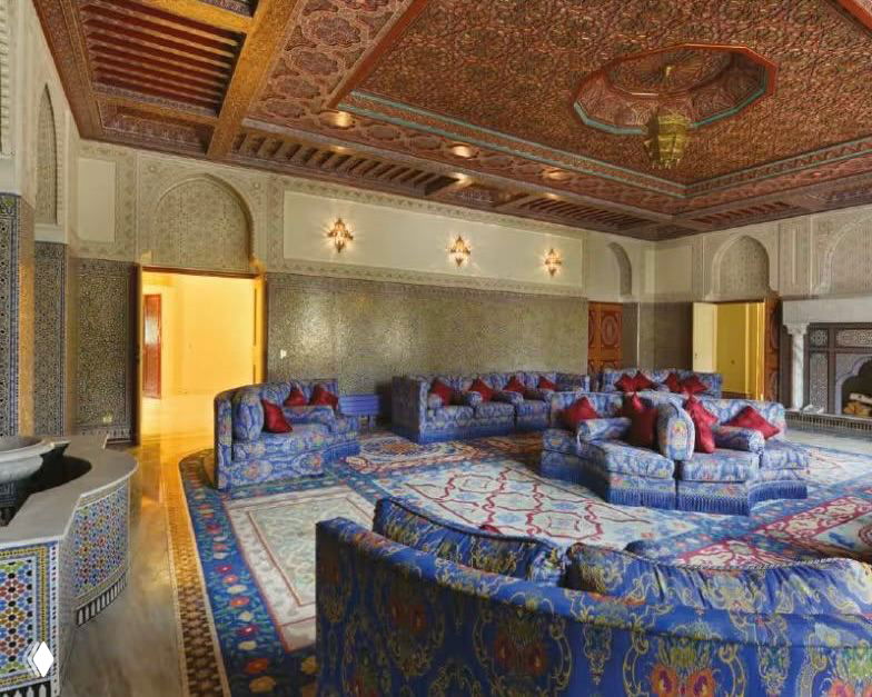 Просторная марокканская гостиная с низкими диванами, мозаичными панелями и богато украшенным потолком — пример восточного интерьера внутри замка