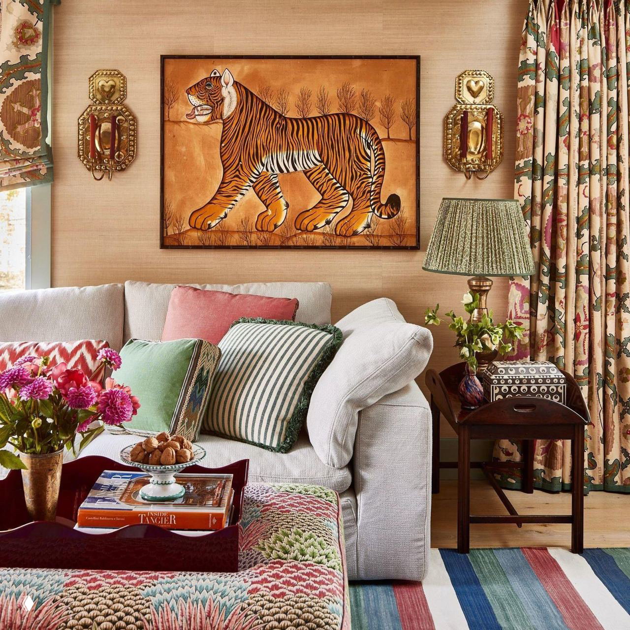 Гостиная с картиной тигра над диваном, множеством декоративных подушек и ярким текстилем в насыщенной палитре.