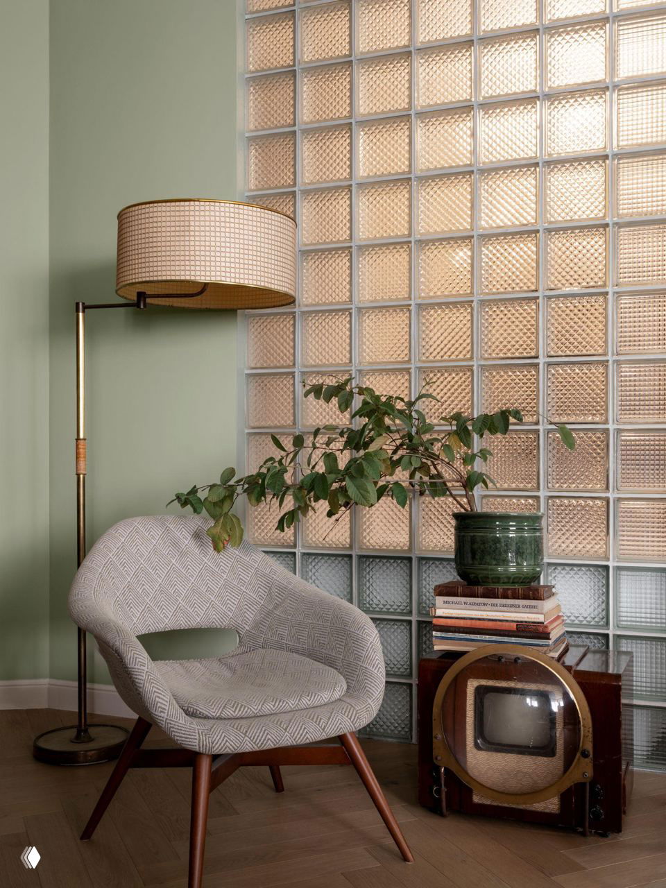 Уютный уголок с креслом, напольной лампой и стеклоблоками в стене; композиция из растений и старинного телевизора создаёт винтажный акцент.