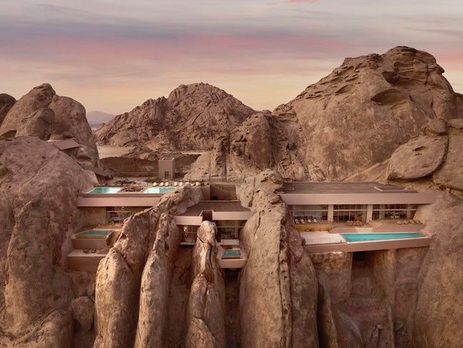 Фасады вилл Desert Rock Resort, встроенные в горные утёсы; бассейны выступают над ущельем, подчёркивая связь архитектуры с рельефом.