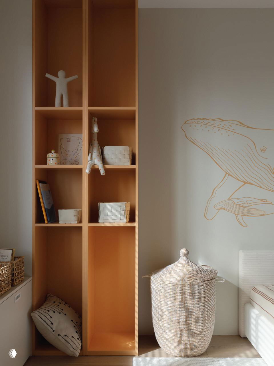 Детская/зона хранения с высокими открытыми полками тёплого терракотового оттенка, плетёная корзина и настенная роспись кита — натуральные материалы и уют.