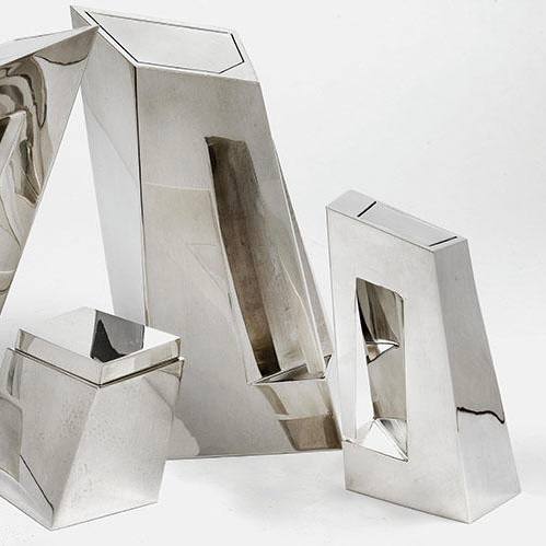 Крупный план полированной металлической формы сервиза с прямоугольным отверстием — минималистичная скульптурная посуда в духе Захи Хадид.