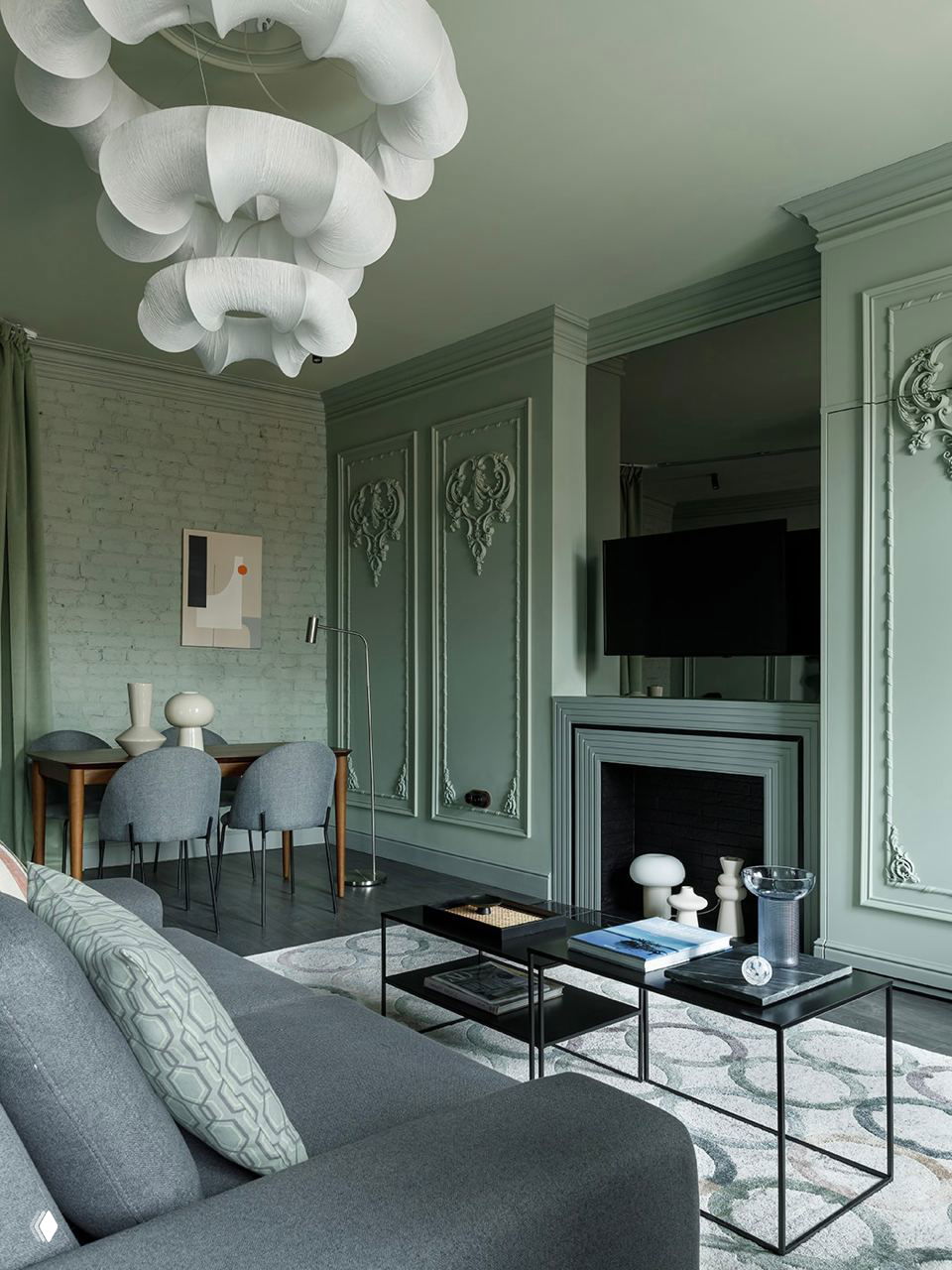 Гостиная в приглушённо‑зелёной палитре с классической стеновой лепниной вокруг камина и фрагментами декоративной розетки на потолке.