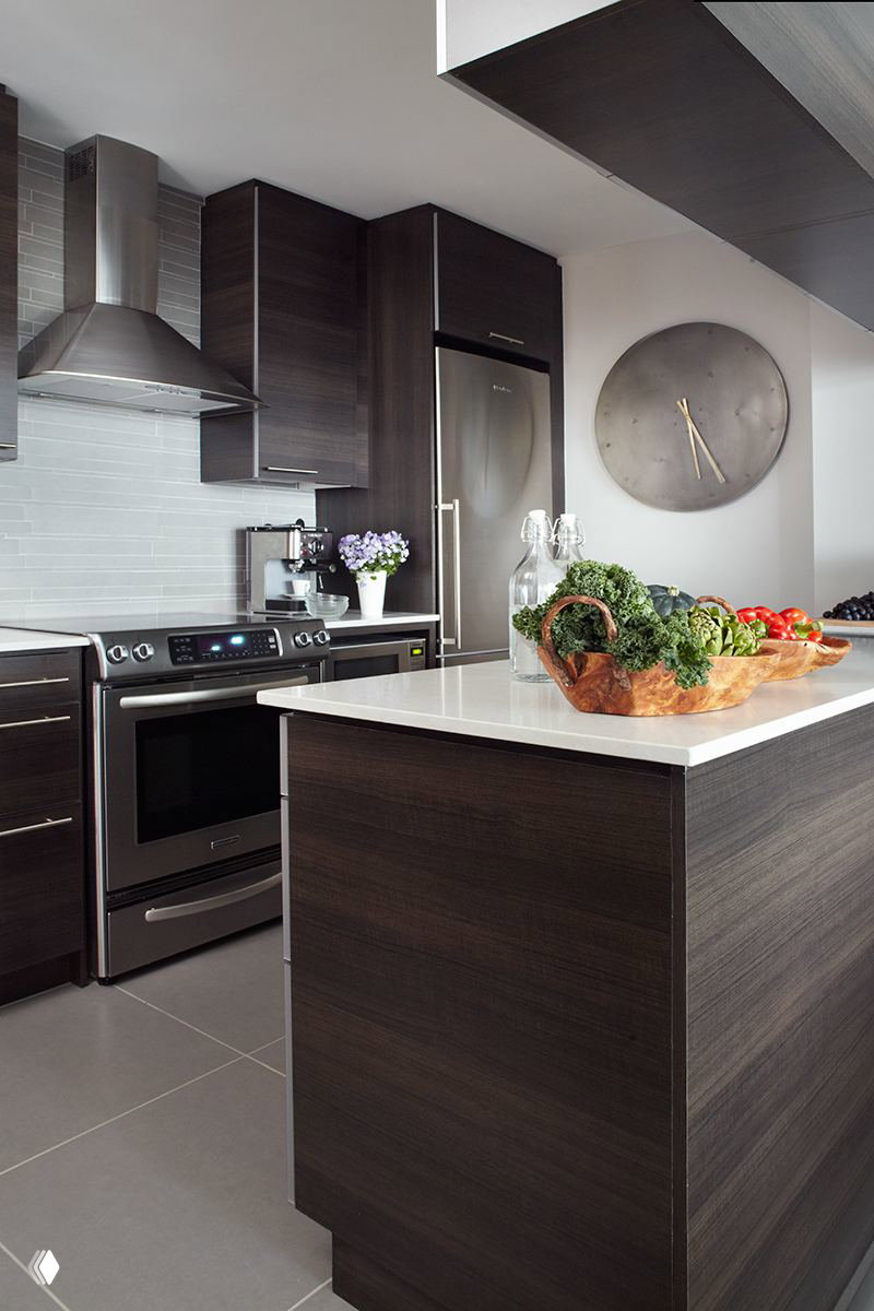 Современная кухня с тёмными деревянными фасадами, встроенной техникой и островом с белой столешницей — сочетание практичности и тёмной текстуры дерева.