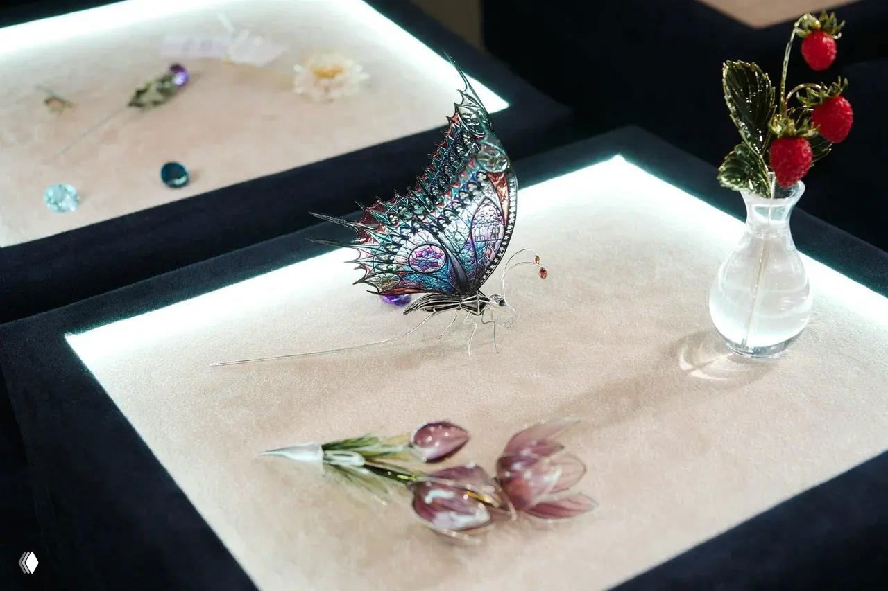 Экспозиция ювелирных украшений: витрины с изящными изделиями, макросъёмка цветочной и бабочковой декоративной броши на подсвеченной бархатной подложке.