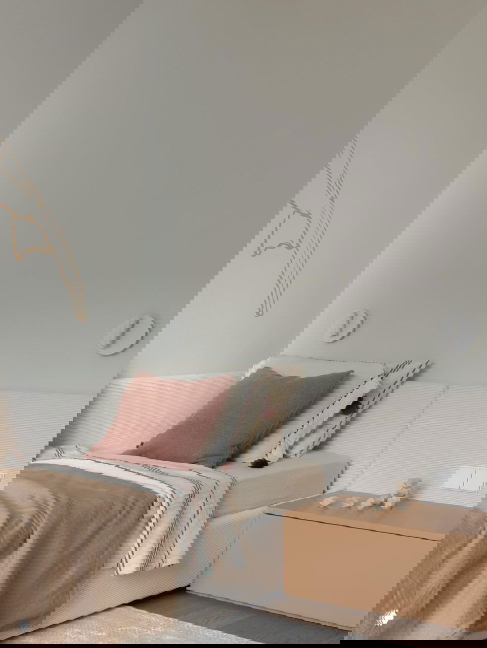 Спальня ребёнка с мягкой низкой кроватью, спокойными пастельными текстилями и подушками; акцент на тактильных материалах и округлых формах.