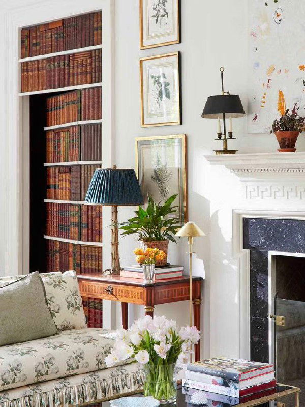 Фальш‑стеллаж с полками и книгами, маскирующий дверцы шкафа в классическом интерьере у камина и декоративного каминного портала.