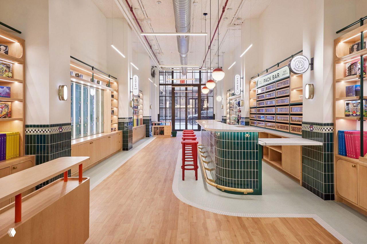 Общий вид длинного и узкого пространства магазина Pokе Court: высокий потолок, открытые воздуховоды, длинная кленовая стойка Pack Bar и красные табуреты.