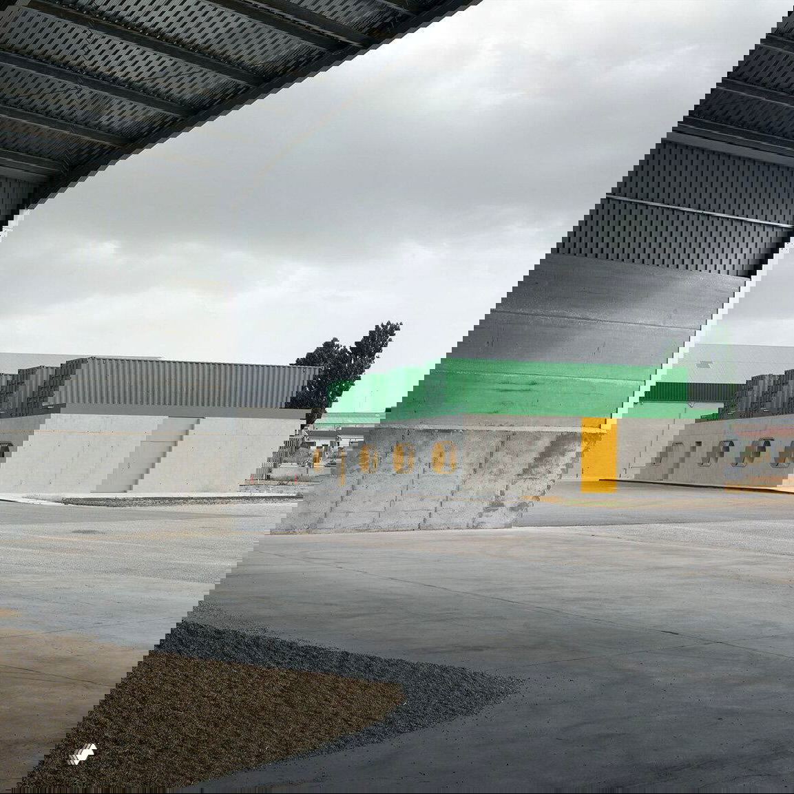 Вид на комплекс с расстояния: четыре прежних морских контейнера зелёного цвета установлены на бетонном основании в индустриальной зоне Куэнки.