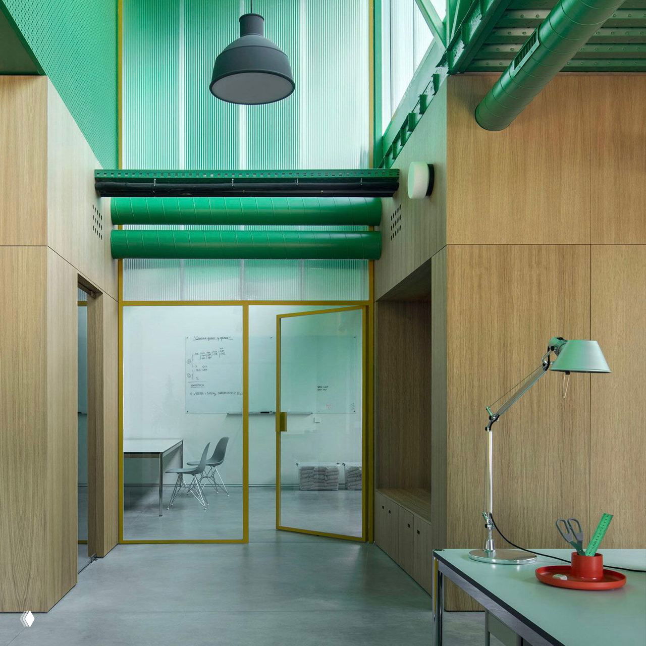 Интерьер офиса: деревянная облицовка, жёлтые стеклянные двери и зелёные светорассеивающие элементы над рабочей зоной с настольной лампой.