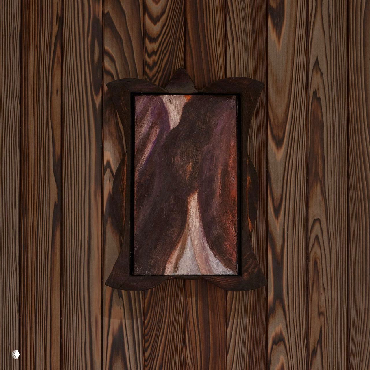 Текстура обугленного кипариса на стенах и небольшая декоративная картина в деревянной раме, подчёркивающие тёплую и минималистичную атмосферу.