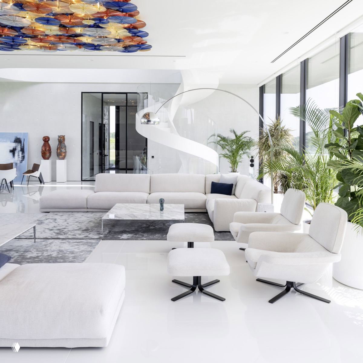 Просторная современная гостиная в белых тонах с белым глянцевым полом, большим угловым диваном и зелеными растениями у панорамных окон.