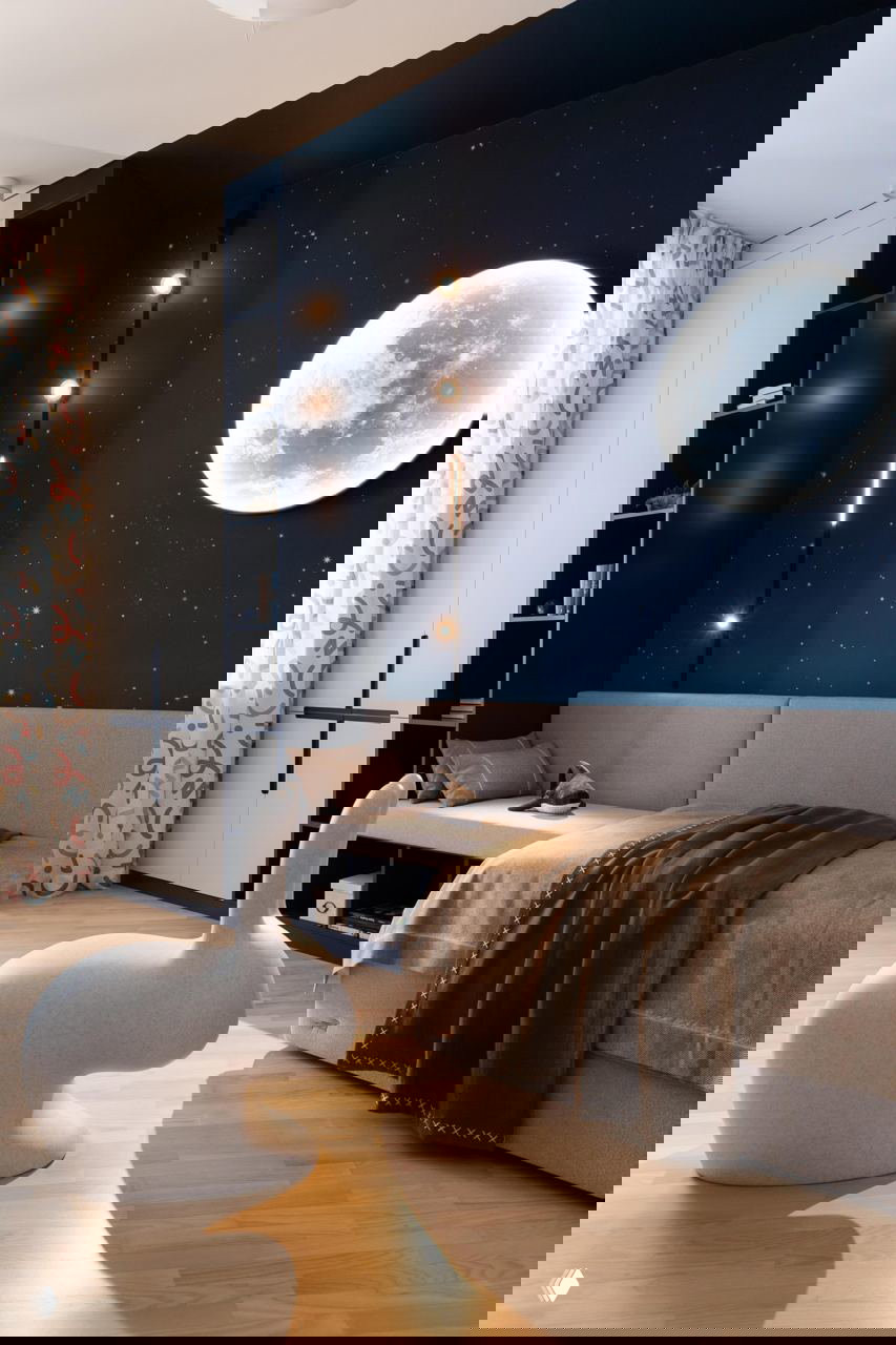 Комната с ночным небом и изображением луны на тёмно-синей стене, мягкая кровать и светлый паркет — яркий акцент в проекте с лунной тематикой.