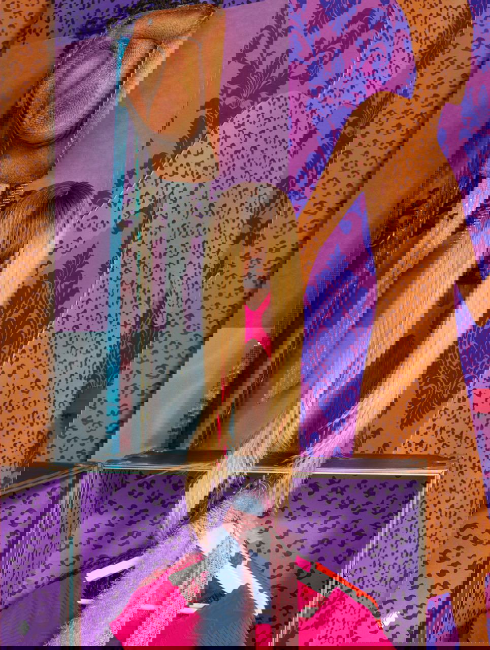 Манекен с длинным париком и стойка с сценическими костюмами: коллекция реквизита и аксессуаров на полках и в ящиках на фоне ярких декоративных обоев.