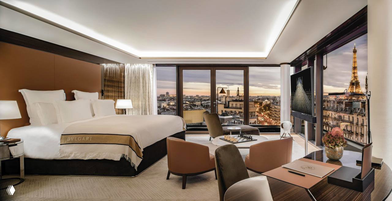 Роскошный номер Bvlgari Hotel Paris: большая кровать, зоны для отдыха и панорамные окна с видом на Эйфелеву башню.