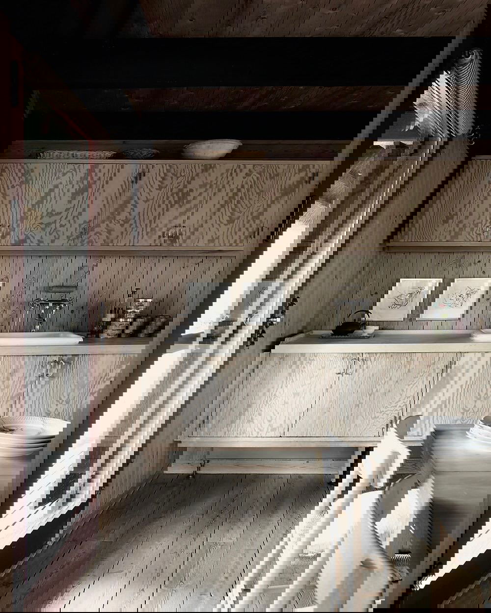 Интерьер с лёгкими фанерными шкафами и паркетом ёлочкой; нижние открытые ниши, декоративные элементы и спокойная цветовая гамма создают уютную кухонную зону.