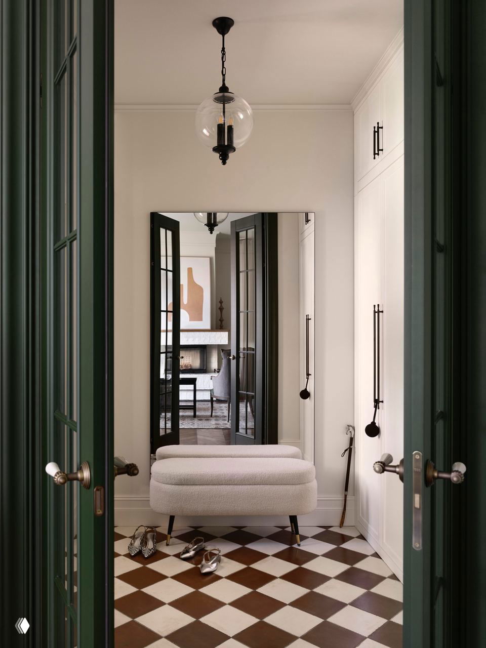 Узкий холл с зелёными дверями, большим зеркалом и пудровым пуфом; в отражении виднеется камин и продолжение интерьера.