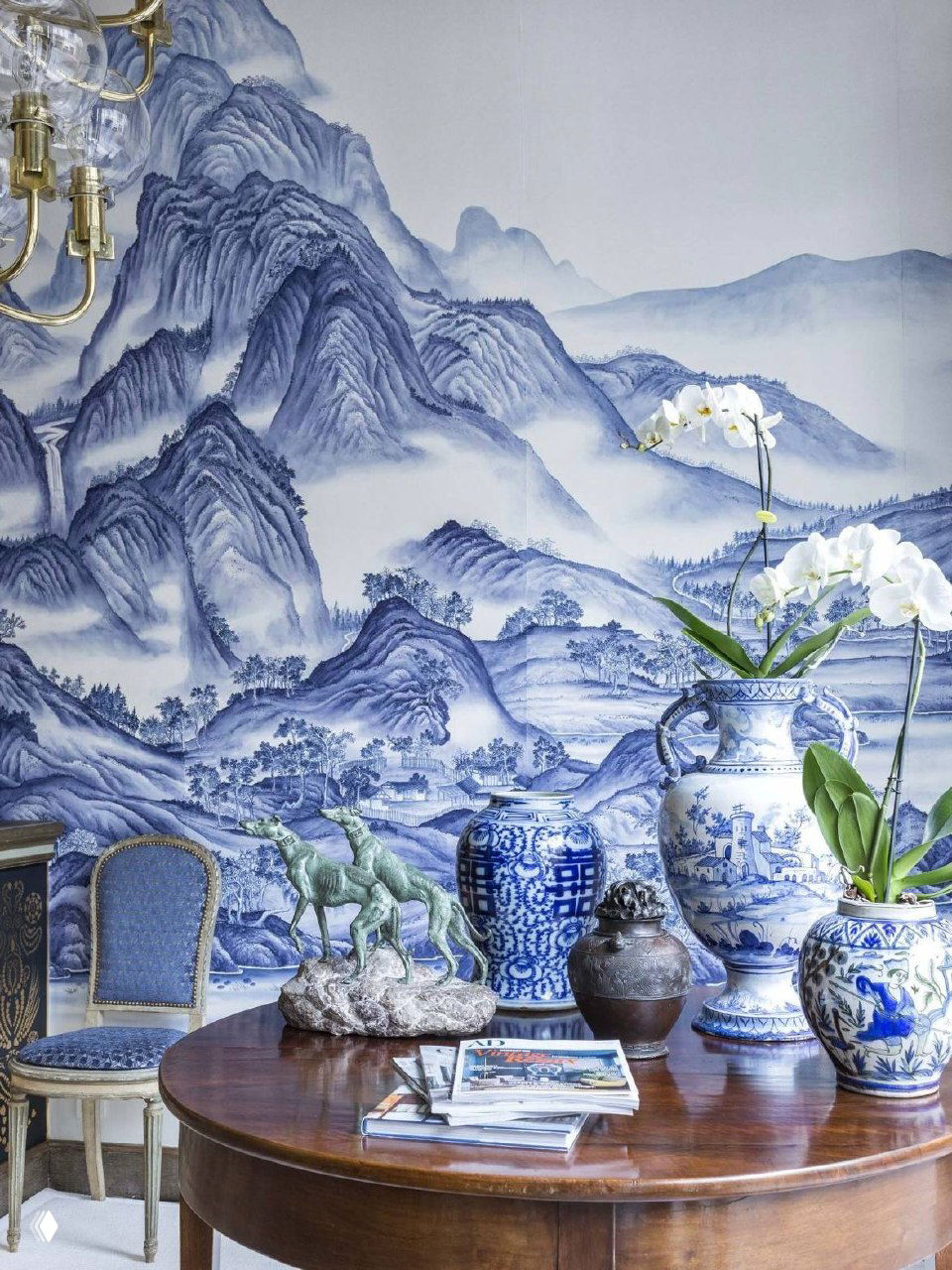 Абстрактный монохромный пейзажный принт на стене, искажённый цифровой эффект в изображении, однако видно декоративное панно и журналы на столе.