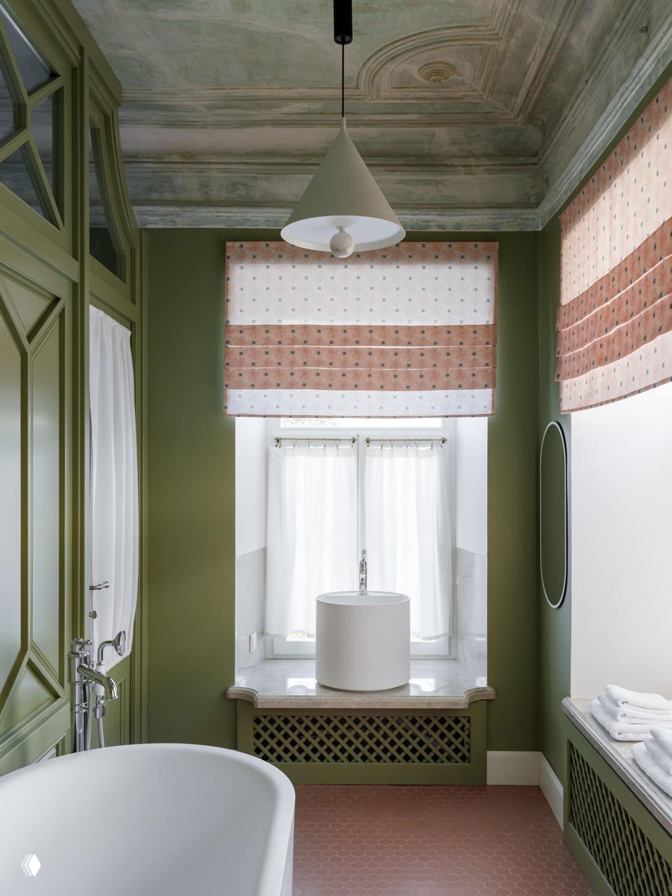 Ванная комната с отдельной ванной, округлой раковиной на подоконнике, розово-коричневой плиткой на полу и римскими шторами на окне в историческом интерьере.