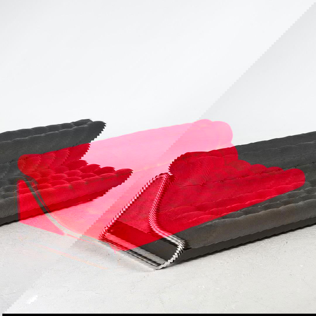 Красный винтажный диван IKEA Impala в боковом ракурсе с яркой бархатистой обивкой, крупными набивными валами и хромированной рамой, студийная фотография мебели.