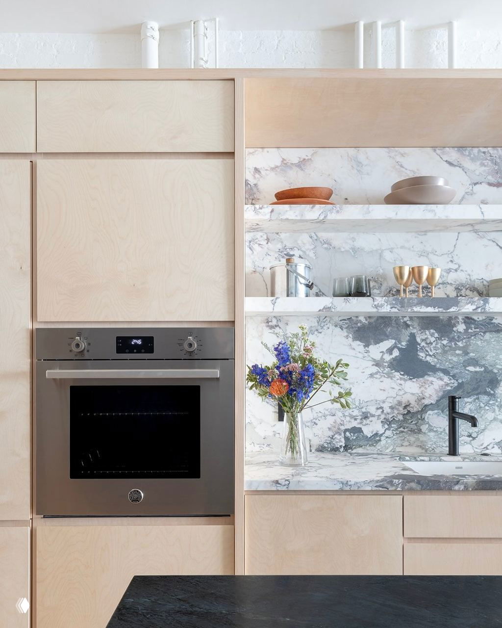 Рустикальная кухня в деревянном доме: фасады и стеновые панели из фанеры в натуральном тоне, простая мойка и деревянный пол подчёркивают фактуру материалов и их естественность.