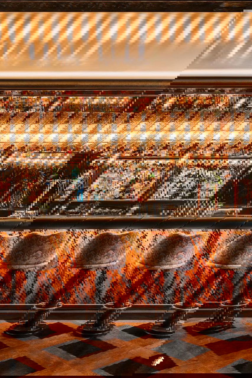 Крупный план барной части: зеркальные полки с коллекцией бутылок, декоративные стеклянные подвески и отделка барной панели в тёплых тонах.