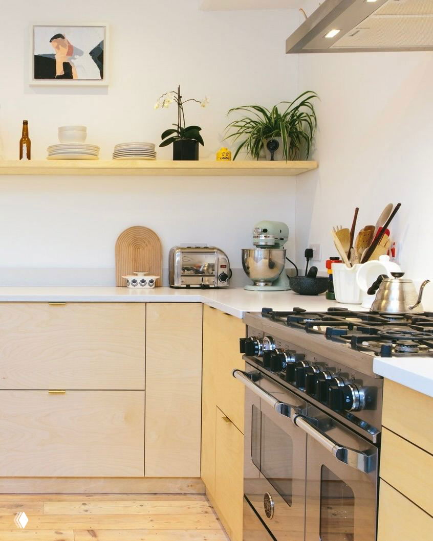 Современная кухня с фасадами из светлой фанеры и мраморным фартуком: встроенный духовой шкаф, открытые полки и акцент на текстуре материалов рядом с рабочей зоной.