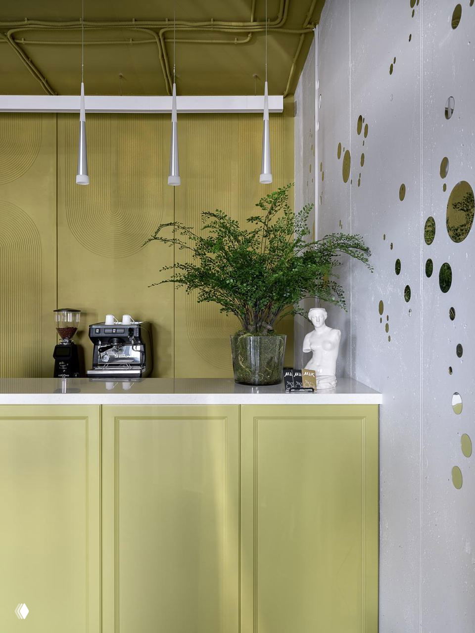 Барная зона и прилавок с кофе-машиной, зелёные панели и ваза с растением — стилизованный интерьер цветочного бутика.