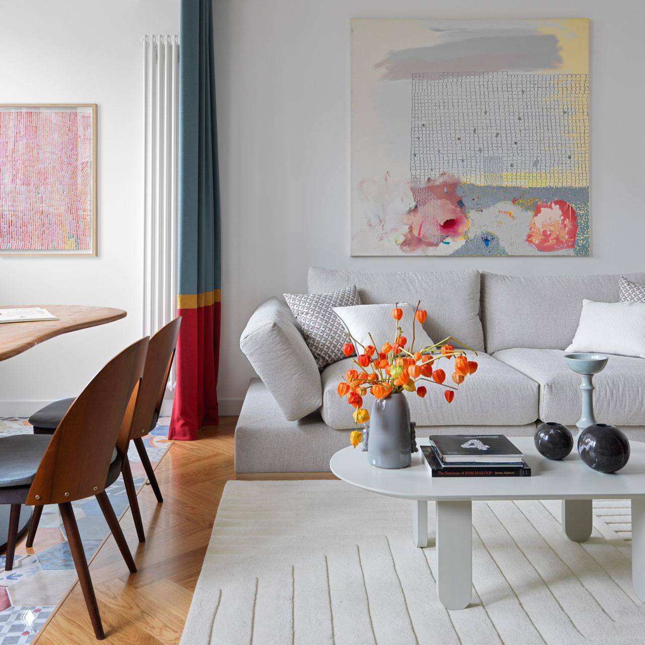 Небольшая светлая гостиная с белым диваном, низким столиком и ярким букетом на столе, сочетание белого фона и цветных акцентов в декоре.