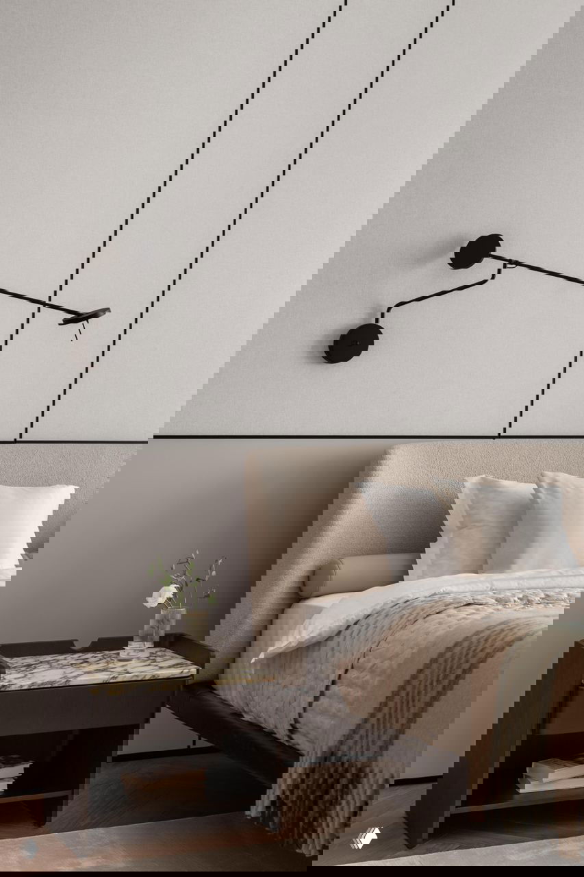 Спальня: мягкое изголовье, прикроватная тумба с мраморной столешницей, настенный чёрный светильник и нейтральный текстиль — акцент на тактильности и спокойствии.