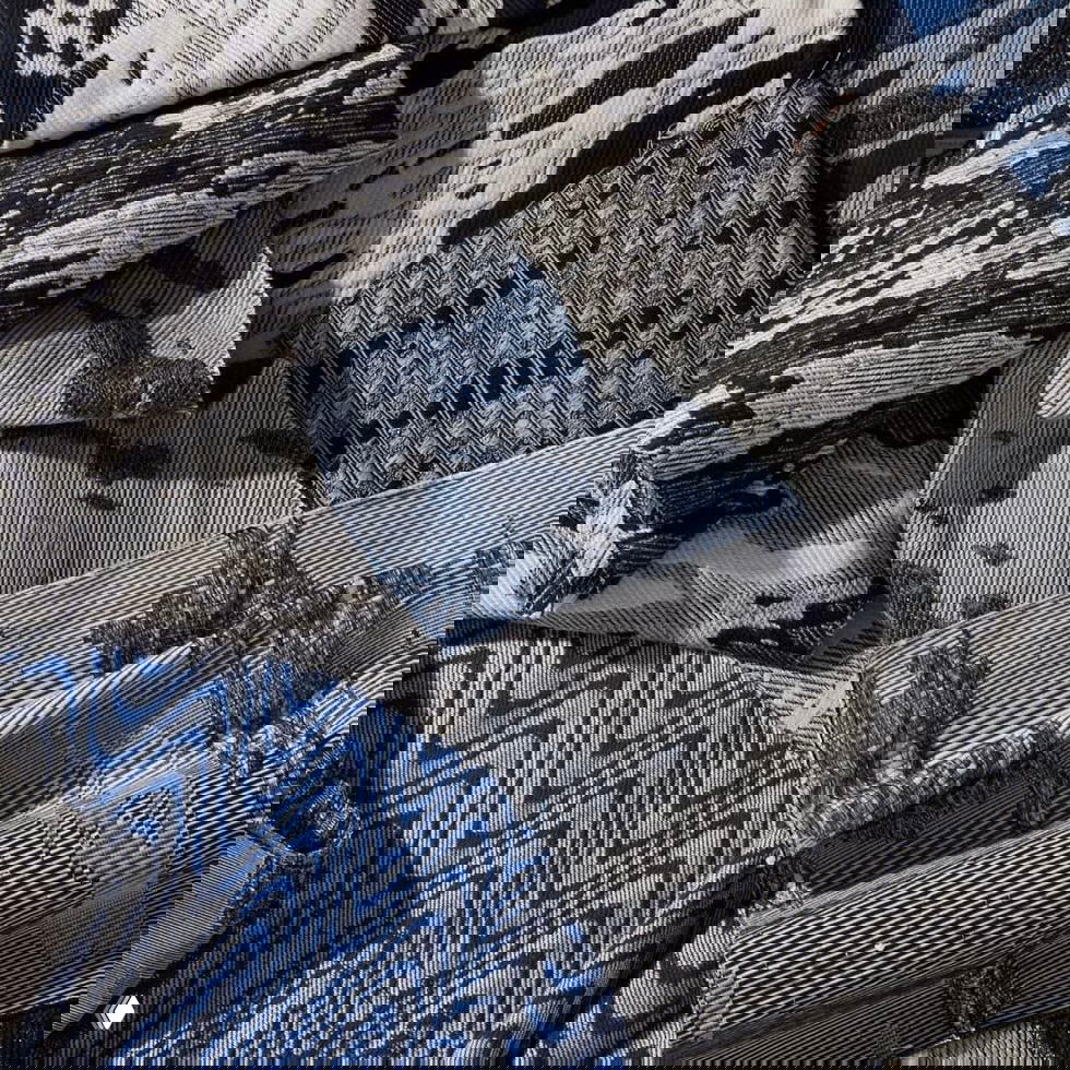 Крупный план образцов тканей Heimtextil: фактурные жаккарды и плетения в сине‑серой гамме, хорошо видна структура нитей и сложные узоры