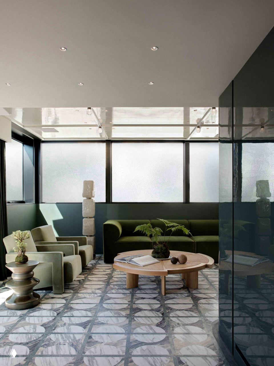 Комната отдыха с зелёным диваном и мраморной плиткой с круглыми мотивами, сочетание текстур и цвета подчёркивает продуманную отделку.