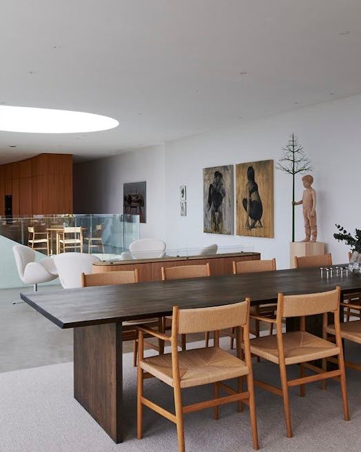 Интерьерная сцена: скульптурное кресло Pelican на фоне кухни с крупным металлическим островом и рифлёной деревянной стеной, минимализм и теплая фактура.