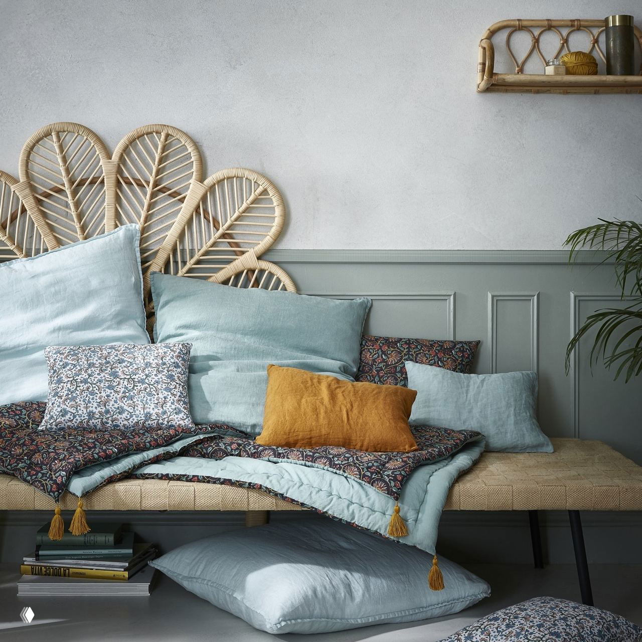 Кровать с плетёным из ротанга в изголовье, мягкими пастельными подушками и покрывалом — вдохновение для спокойной спальни в уютном светлом стиле
