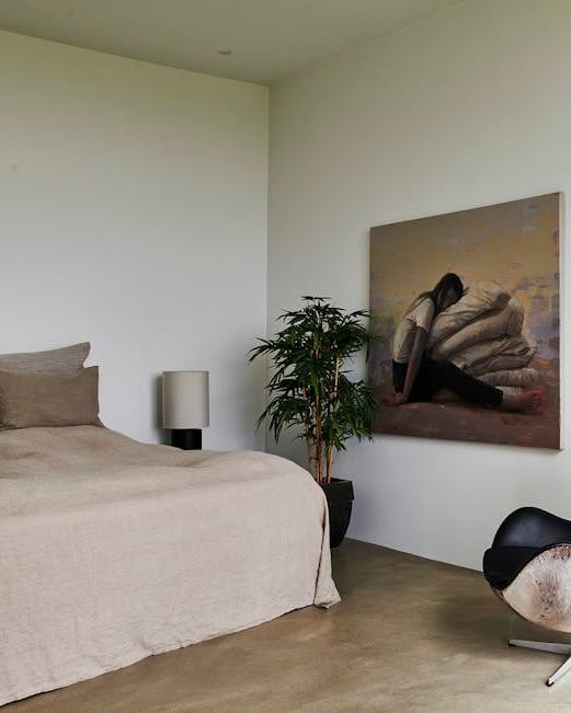 Обеденная зона виллы с длинным деревянным столом и стульями в скандинавском стиле, на заднем плане художественные работы и открытая планировка.