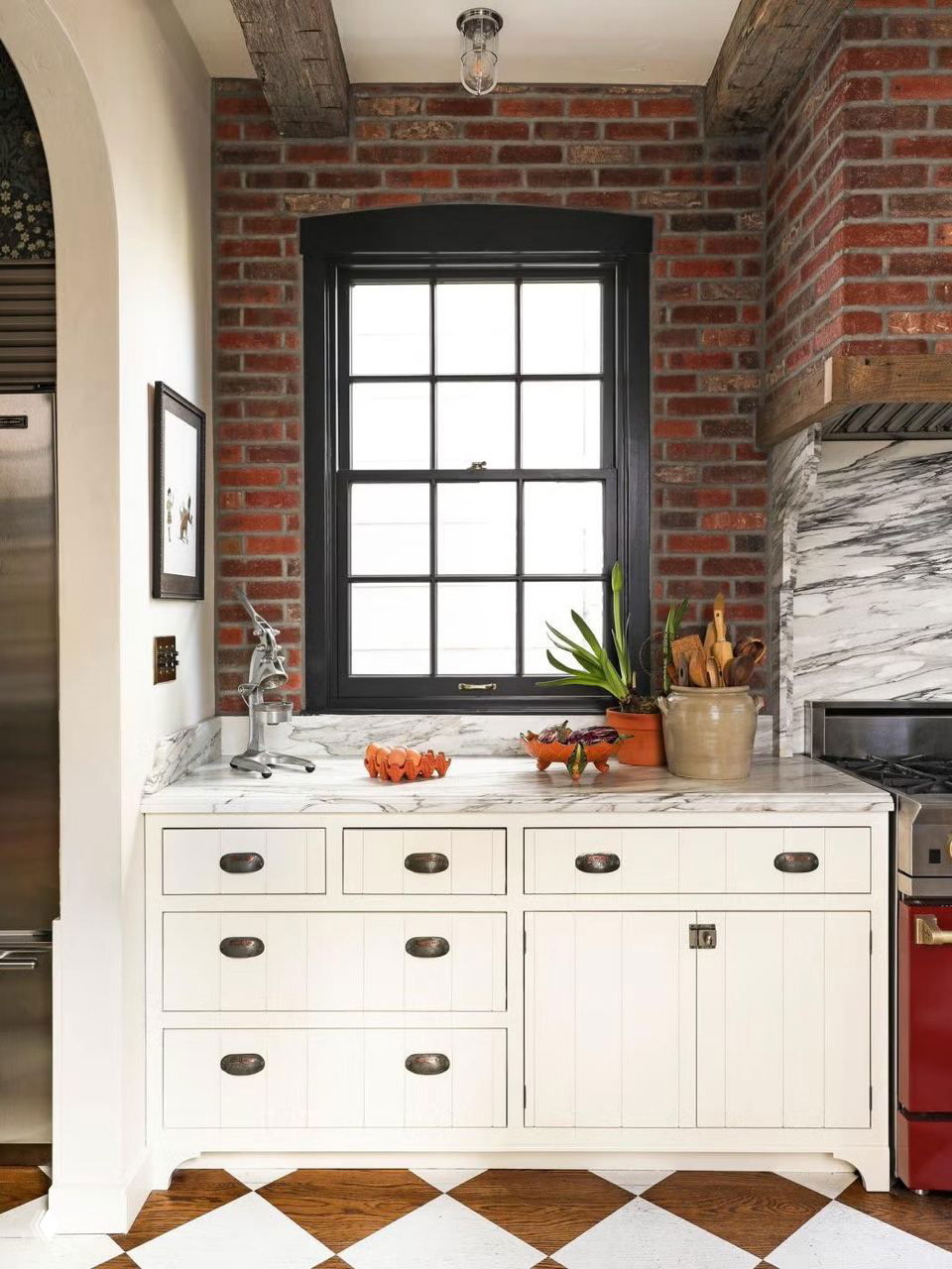 Интерьер с кирпичной стеной и контрастной чёрно-белой ромбовидной укладкой пола, деревянные фасады и мраморная столешница