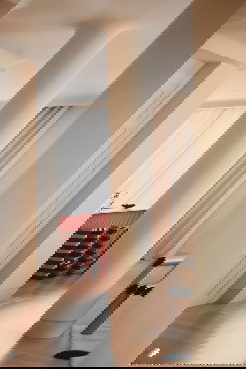 Интерьер с округлыми колоннами и видом на часть кухни: светлые стены, паркет и мебель в минималистской средиземноморской манере.