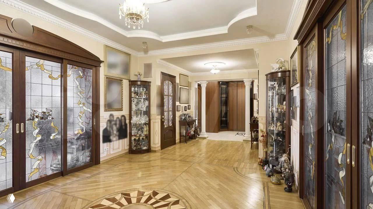 Коридор с деревянными дверями и витражами, шкафы-витрины и классическая отделка стен — интерьер в стиле 2000-х с музейной экспозицией сувениров.