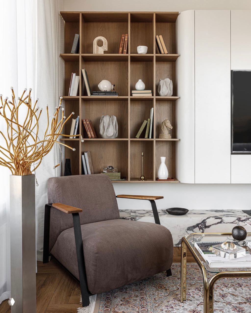 Уютная комбинация зоны отдыха и навесных полок из натурального дерева, декоративные предметы и кресло винтажного характера на фоне мраморной панели.