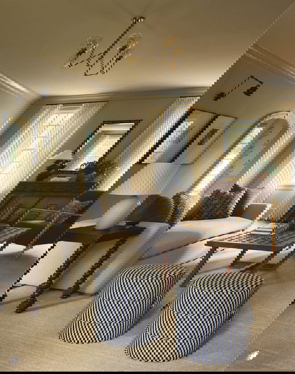 Гостиная с нейтральным диваном, деревянным кофейным столиком и мягкими текстурами, естественный свет из высоких окон и спокойная классическая палитра интерьера.