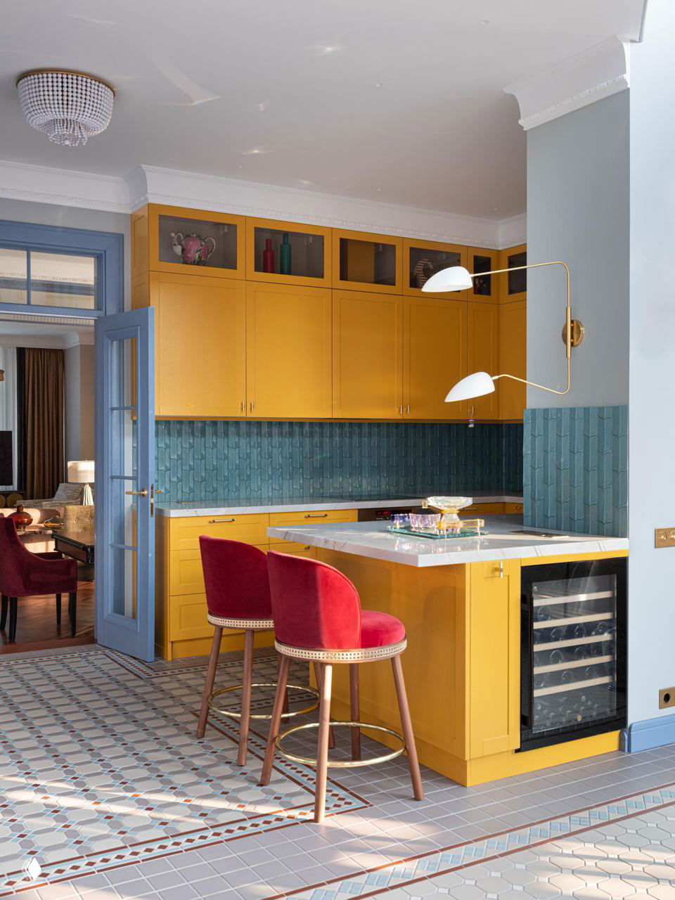 Яркая кухня с жёлтой мебелью и декоративной мелкой плиткой на полу в тон, барные стулья с красной обивкой создают цветовой акцент