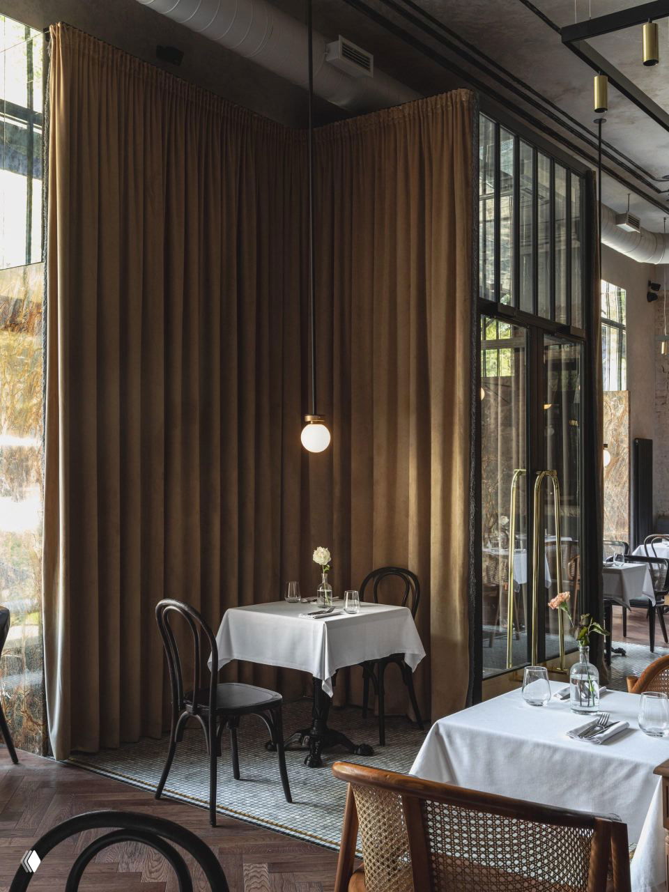 Интимный столик у плотных бархатных штор: подвесной светильник, стол со скатертью и тёплые текстуры дерева и плитки вокруг.