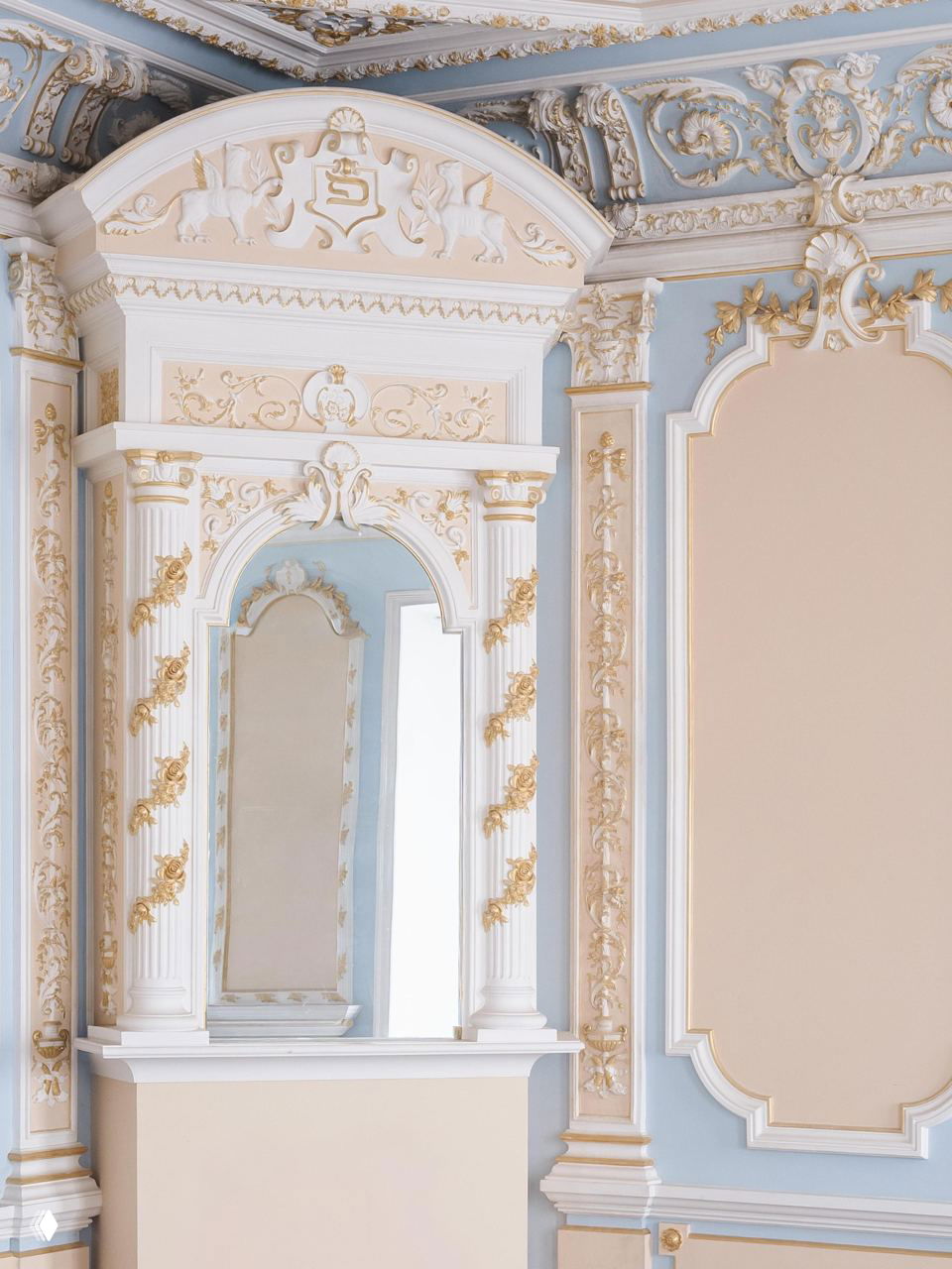 Классический парадный зал усадьбы: дверной проём, пилястры и позолоченные декоративные элементы на стенах и карнизах, выдержанные в спокойной пастельной палитре.