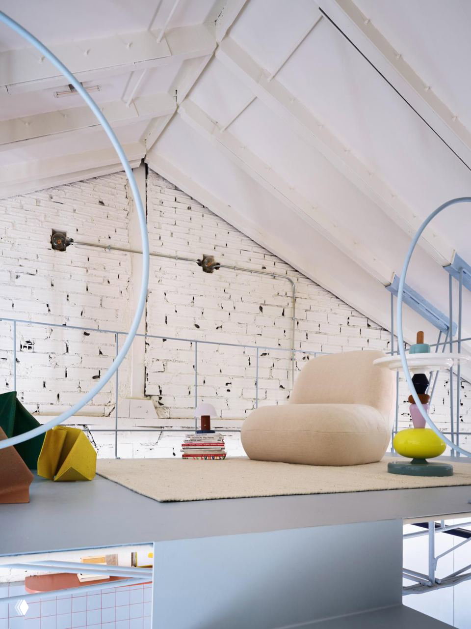 Верхний лёгкий уровень площадью 18 м²: низкое кресло, коврик и ограждение; белая побелённая кирпичная стена и тонкая стальная конструкция перекрытия.