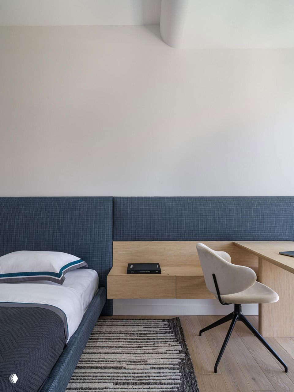 Комната с низким изголовьем и рабочим местом у кровати: текстуры тканей и древесные оттенки создают спокойную атмосферу для семьи.