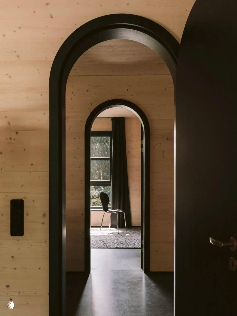 Коридор и арочные проёмы внутри деревянного дома Atelier ST: отделка из ели, тёплый тон древесины и чёрные обрамления дверей.